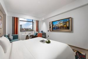a hotel room with a white bed and a tv at Insail Hotels Guangzhou Beijing Road Pedestrian Branch in Guangzhou