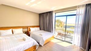 a bedroom with two beds and a large window at Minh An Villa in Da Thanh