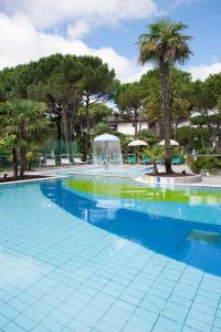 une grande piscine avec des palmiers et une fontaine dans l'établissement Hotel Delle Nazioni, à Lignano Sabbiadoro