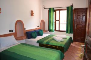 a bedroom with two beds with green and white at Hôtel Restaurant La Gazelle De Dades in Akhendachou nʼAït Ouffi