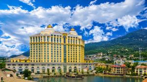 a large yellow building next to a body of water at 泰安宝龙艺珺酒店 in Tai'an