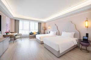 a hotel room with two beds and a living room at Mercure Urumqi Doowin Wanda Plaza in Ürümqi