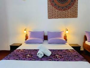 a bedroom with a bed with purple pillows at Happy Beach hotel nilaveli in Nilaveli +160 photos