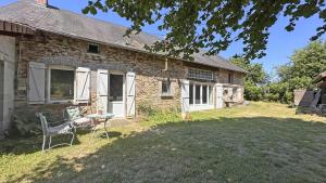 a stone house with two chairs and a table in the yard at L'humeur vagabonde in Linards