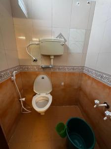 a bathroom with a toilet and a green bucket at IP Home stays in Pondicherry