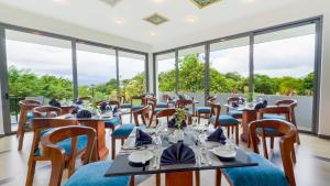 a restaurant with tables and chairs and large windows at Hasthi Boutique in Kandy