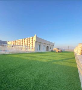 a building with a yard with green grass and buildings at استراحة الروابي in Salalah