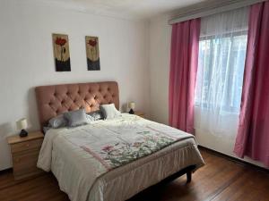 a bedroom with a large bed with pink curtains at HOSTEL Gloria Economy in Viña del Mar