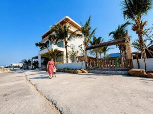 a woman walking down a street in front of a house at An Hải Beachfront Retreat Ninh Thuận in Thôn Dư Khánh