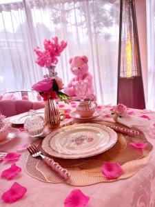 a teddy bear sitting at a table with a pink table cloth at Pink Village Boutique in Campos do Jordão