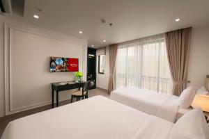 a hotel room with two beds and a desk at Euphoria Hotel & Spa in Hanoi