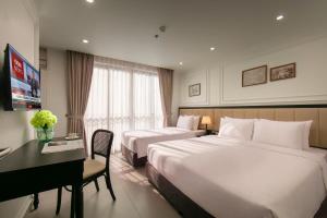 a hotel room with two beds and a desk at Euphoria Hotel & Spa in Hanoi