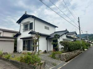 a white house sitting on the side of a street at Folk-ish Style 風 in Miyazu