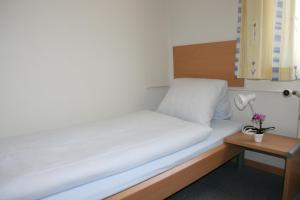 Cama en habitación pequeña con lámpara y mesa en Hotel Glärnisch Hof en Horgen