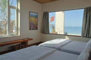 a bedroom with two beds and a large window at An Hải Beachfront Retreat Ninh Thuận in Thôn Dư Khánh