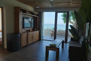 a living room with a television and a view of the ocean at An Hải Beachfront Retreat Ninh Thuận in Thôn Dư Khánh