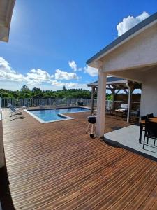 a wooden deck with a pool and a pavilion at Sun House in Grand-Bourg