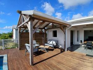 a pergola on a deck with a table and chairs at Sun House in Grand-Bourg
