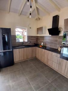 a kitchen with a black refrigerator and wooden cabinets at Sun House in Grand-Bourg