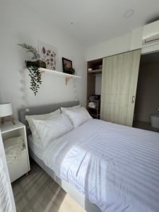 a bedroom with a large bed with white sheets at Avrora Laguna Residences Sky Park in Ban Thalat Choeng Thale