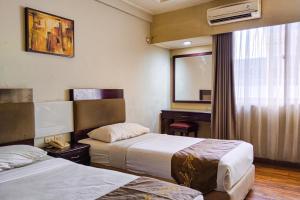 a hotel room with two beds and a mirror at SNUZ Hotel Menteng in Jakarta