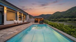 a house with a swimming pool next to a river at Hongcheon Around River Poolvilla Pension in Mangdani
