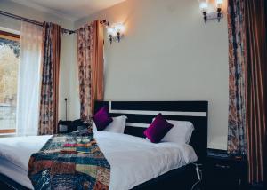 a bedroom with a large bed with purple pillows at Samoon Guest House Sonmarg in Kulan +6 photos