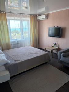 a bedroom with a bed and a flat screen tv at Квартира ЛЮКС in Balqash