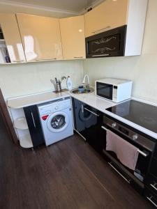 a kitchen with a washing machine and a microwave at Квартира ЛЮКС in Balqash