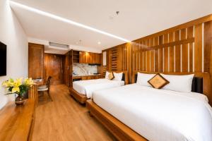 two beds in a room with a desk and a kitchen at Mixay Boutique Hotel Da Nang in Danang
