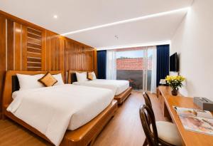 two beds in a room with a desk and a table with a desk at Mixay Boutique Hotel Da Nang in Danang