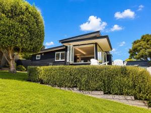 a house with a hedge in front of it at Smiths Cottage - Stay Waiheke in Oneroa +11 photos