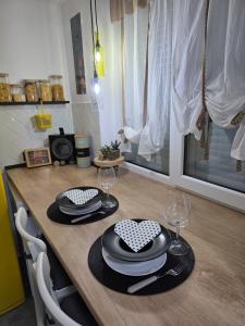 a wooden table with plates and wine glasses on it at Ssalamandra home's in Ocna-Mureşului