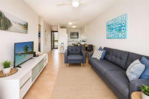 a living room with a blue couch and a tv at Warroo Apartments in Alexandra Headland
