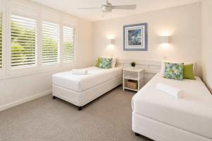 a living room with two white beds and a window at Warroo Apartments in Alexandra Headland +2 photos