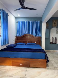 a bedroom with a large wooden bed with blue sheets at Nandbhavan Guruvayur in Guruvāyūr