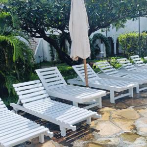 a row of white lawn chairs with an umbrella at Summer Studio Suit in Malindi