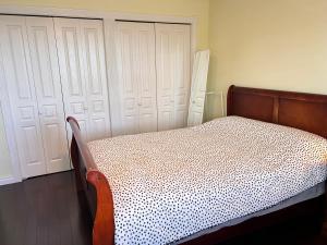 a bedroom with a bed and two white garage doors at Sandy's Sweet Home in Coquitlam