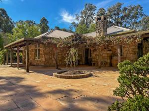 a stone house with a tree in front of it at Highwoods Cottage in Pokolbin