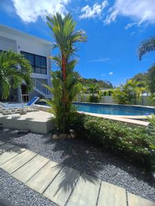 a palm tree in front of a building with a swimming pool at Lamai Sunshine Villas in Hua Thanon Beach +39 photos
