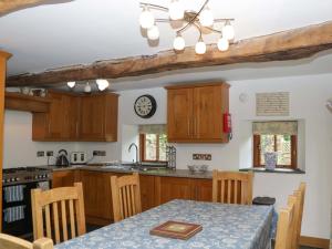 a kitchen with wooden cabinets and a table with a table cloth at The Hay Barn in Halwell