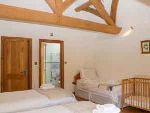 a room with two beds and a crib in it at The Hay Barn in Halwell +34 photos