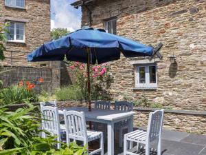 a table and chairs with a blue umbrella at The Hay Barn in Halwell