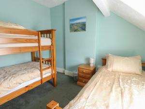 a bedroom with two bunk beds and a night stand at Halford Hill in Llanberis