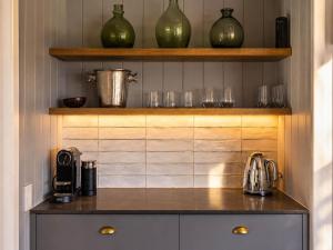 a kitchen with a counter with glasses on shelves at Smiths Cottage - Stay Waiheke in Oneroa