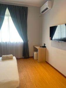 a room with a bed and a window and a television at DBC Hotel in Semporna
