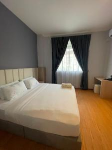 a large white bed in a room with a window at DBC Hotel in Semporna