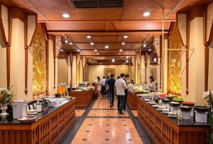 a buffet line in a restaurant with people walking around at Golden Beach Hotel Pattaya in Pattaya