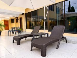 two chairs and an umbrella in front of a building at EXECUTIVE SUITE Piscina & Parking Privado in Machala