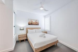 a white bedroom with a bed and a window at C Bargara Unit 101 in Bargara +18 photos